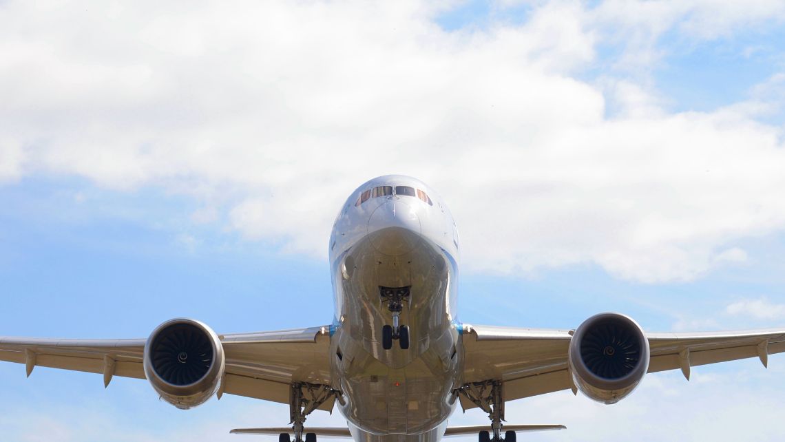 Primer plano frontal de un avión comercial en pleno vuelo bajo un cielo azul con nubes blancas dispersas. AERA clúster aeronáutico Aragón